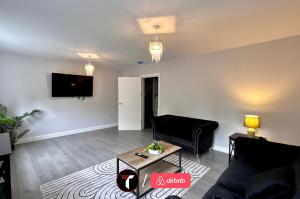 a living room with a couch and a tv on a wall at Spacious 4 Bedroom House for 8 Guests Ideal for Families and Contractors, WIFI and Free Parking in Aldershot