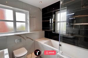 a bathroom with a tub and a toilet and a window at Spacious 4 Bedroom House for 8 Guests Ideal for Families and Contractors, WIFI and Free Parking in Aldershot