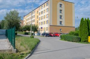 a building with cars parked in a parking lot at Apartament przy Wolnej in Sanok