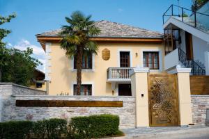 a house with a palm tree in front of it at Nostalgia Boutique Hotel in Gjirokastër