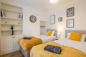 two beds in a room with a clock on the wall at 4 BDR I sleeps 8 I Wi-FI I Free Parking I Central in CBG