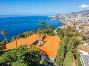 une maison au toit orange sur une colline surplombant l'océan dans l'établissement PRIVATE OCEANFRONT DELUXE VILLA PICO 360 VIEWs, à Bicas