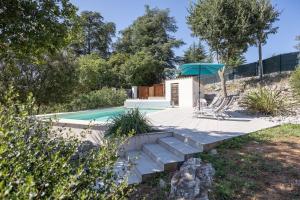 una piscina con patio y sombrilla en DOMAINE VILONAPA - villa Figuier, en Saint Alban Auriolles