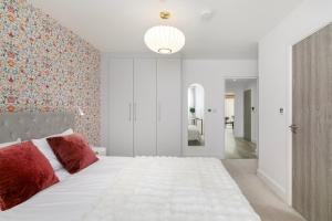 a bedroom with a large white bed with red pillows at New in Willesden close to Oxford Str, Wembley, Jubilee line in London