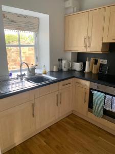 a kitchen with wooden cabinets and a sink and a window at May Cottage in Anstruther