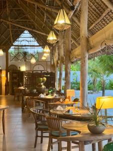 un restaurant avec des tables et des chaises en bois et des lumières dans l'établissement Infinity Beach Boutique Hotel & SPA, à Matemwe