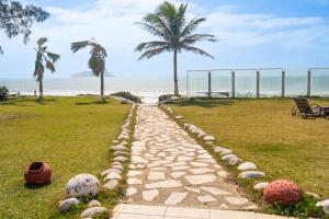 Un camino de piedra que conduce a la playa con palmeras. en HANNA Búzios Al Mare Hotel, en Búzios