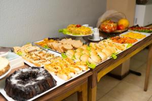 a table filled with different types of sandwiches and other foods at HANNA Búzios Al Mare Hotel in Búzios
