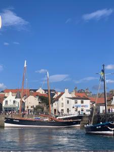 two boats are docked in the water near a city at May Cottage in Anstruther +7 photos