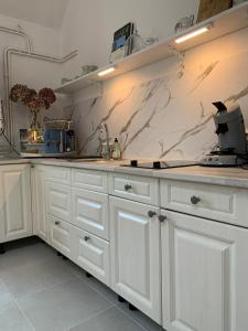 a kitchen with white cabinets and a marble wall at La petite maison in Solesmes