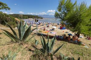 a beach with a bunch of people sitting on the sand at Apartments Meri - 1 in Lopar