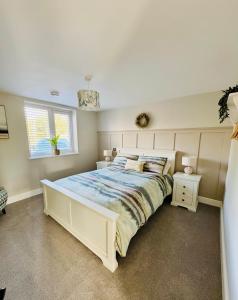 a bedroom with a large white bed and a window at Seaside Getaway - Roebuck Cottage in Reighton