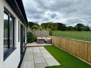 a patio with a couch and a table and a fence at Seaside Getaway - Roebuck Cottage in Reighton