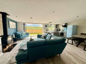 a living room with a blue couch and a kitchen at Seaside Getaway - Roebuck Cottage in Reighton