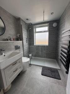 a bathroom with a tub and a sink and a toilet at Seaside Getaway - Roebuck Cottage in Reighton +23 photos