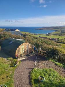 a greenhouse on a hill with a view of the ocean at Butterfly PODika in Lerwick