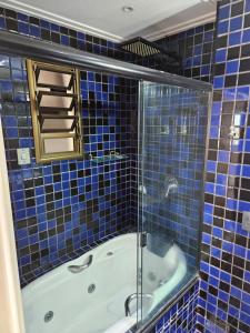 a blue tiled bathroom with a tub and a shower at Ed Plaza Viena Apto 3 Quartos Vista Mar in Florianópolis