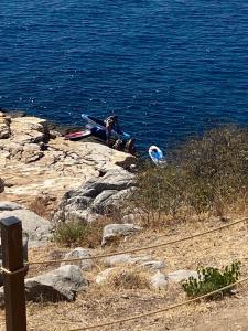 une personne assise sur les rochers près de l'eau dans l'établissement Acroterra - Easy Living, à Alikí