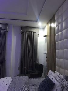 a bedroom with a bed and a chair and curtains at Nin Lux suites in Lekki
