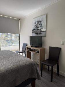 a hotel room with a bed and a desk with a television at Depto a 2 pasos Mall Parque Arauco 301 in El Cerrillo