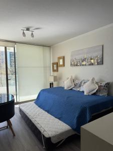 a bedroom with a blue bed and a window at Depto a 2 pasos Mall Parque Arauco 301 in El Cerrillo
