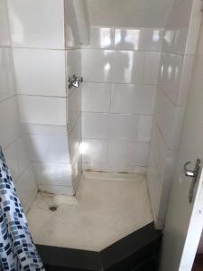 Łazienka z prysznicem wyłożona jest białymi kafelkami. w obiekcie Cozy Corner w Kapsztadzie