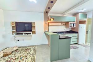 a kitchen with a counter and a tv in it at Firenze Beach House AP101 - 500m da Praia + Wifi in Navegantes +9 photos