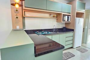 a kitchen with green cabinets and a white refrigerator at Firenze Beach House AP101 - 500m da Praia + Wifi in Navegantes
