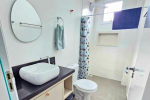 a bathroom with a sink and a toilet and a mirror at Firenze Beach House AP101 - 500m da Praia + Wifi in Navegantes