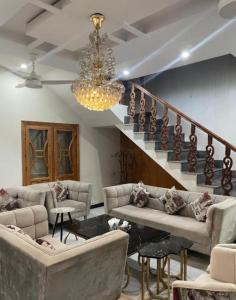 a living room with couches and a staircase with a chandelier at Couple Friendly Guest House in Karachi