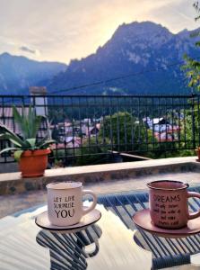 two coffee cups sitting on a table on a balcony at Mont'Arte - Private Art retreat Villa in Buşteni