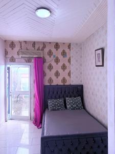 a bedroom with a purple bed and a window at Appartement de 2chambres in Kofa