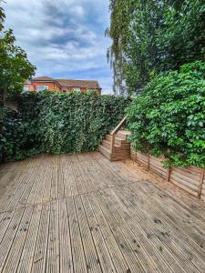 a wooden deck in front of a green hedge at Modern Central Flat with Garden & Parking in Southampton