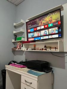 a computer desk with a tv on a wall at Kitnet COP30 in Ananindeua