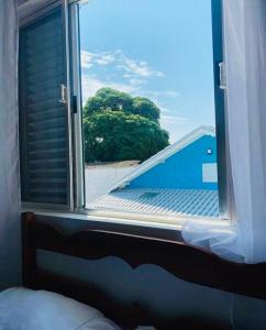 ein Fenster in einem Zimmer mit Blick auf einen Baum in der Unterkunft Pousada Lume Beach House Peruíbe in Peruíbe