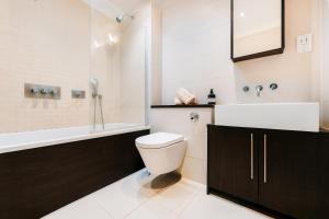 a bathroom with a toilet and a sink and a tub at Loft Apartment in Farringdon with a Terrace in London +49 photos