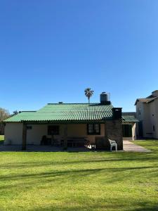 a house with a green roof and a grass field at La Quinta de Areco in San Antonio de Areco