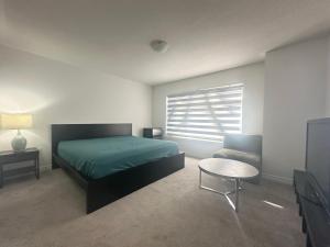 Un dormitorio con una cama y una mesa y una ventana. en Keppel Circle Residence, en Brampton