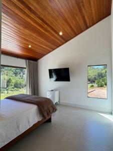a bedroom with a bed and a flat screen tv at Casa Uliana Aracê Pedra Azul in Domingos Martins