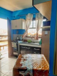 una cucina con pareti blu e un tavolo in una stanza di kitnet Conjugado em Tramandai a Tramandaí