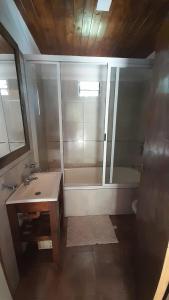 Un baño con bañera, lavabo y espejo. en La casita del bosque, en Valeria del Mar