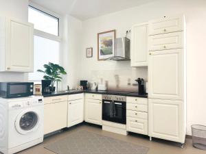 a kitchen with white cabinets and a washer and dryer at Hollywood Apartment XXL in Bremerhaven