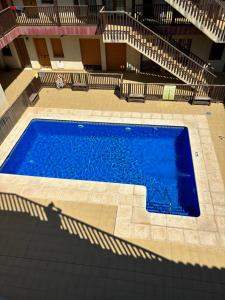 a large blue swimming pool in a building with stairs at Apartamento Torres in Las Bombardas