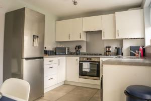 a kitchen with white cabinets and white appliances at JustStay Glasgow - 3 Bedroom Luxury Villa with free parking in Bailleston +26 photos
