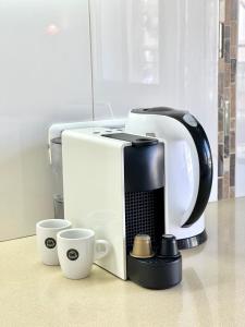 a white coffee maker and two cups on a counter at Bat Galim - luxury apartment by the sea in Haifa +28 photos