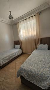 a bedroom with two beds and a window at Jad Appartement N1 in Essaouira