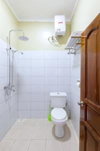 a white bathroom with a toilet and a shower at Equinox Vacation Apartments in Bulambiro +43 photos
