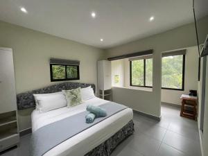 a bedroom with a large bed and two windows at The Blue Eco Lodge in Valladolid