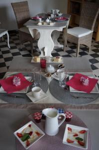 a table with plates of food and cups and a table with a tableablish at Le Clos Saint Jean in Sainte-Honorine-des-Pertes