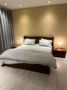 a bedroom with a large bed with two lamps on tables at Luxury Soundproof Apt, MM Alam Road, Gulberg in Lahore +11 photos